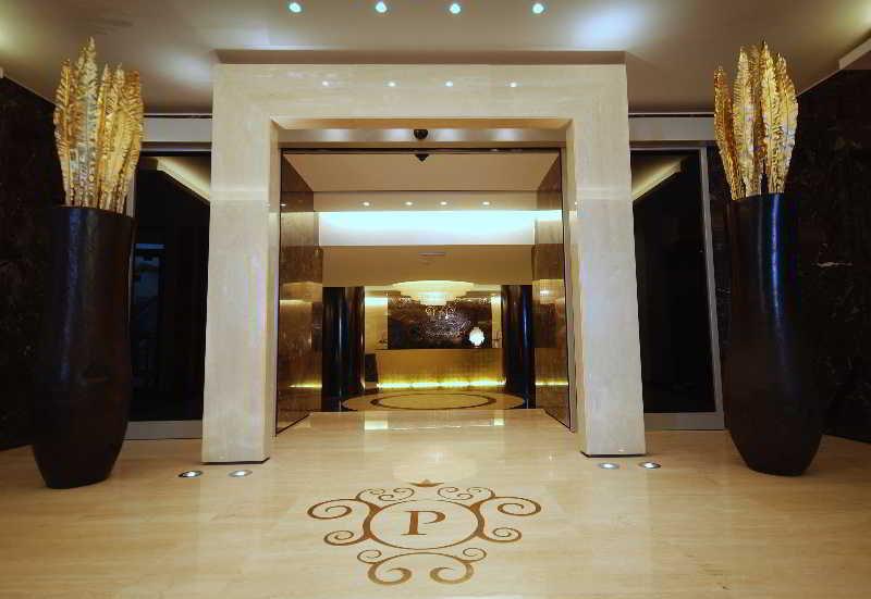 Grand Hotel Bernardin Portoroz Exterior photo The photo shows an elegant entrance to a lobby. There is a large, ornate archway made of light-colored stone, leading into a well-lit area. On either side of the entrance, there are tall, dark vases that contain decorative golden elements resembling 