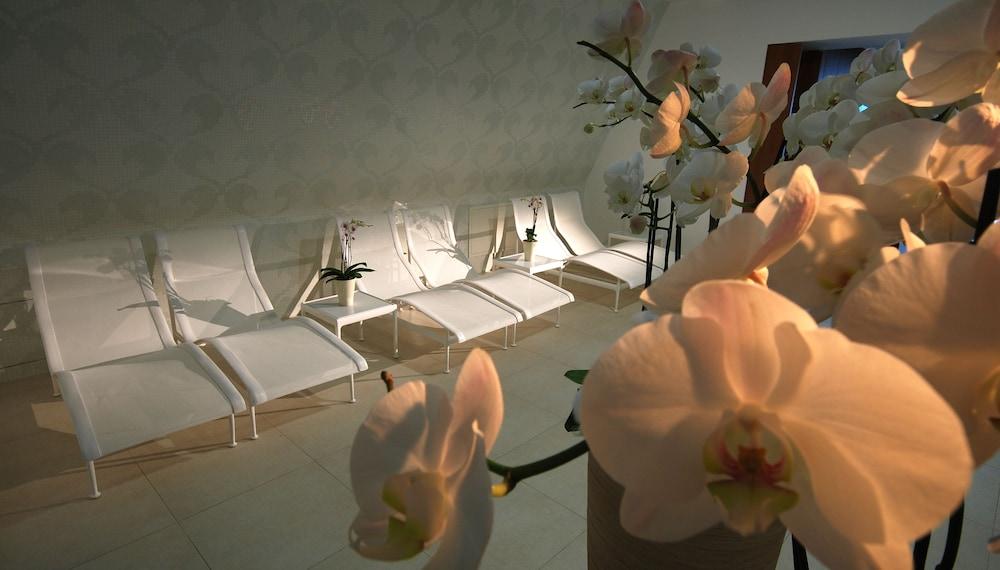 Grand Hotel Bernardin Portoroz Exterior photo The photo shows a serene indoor space designed for relaxation. In the foreground, there are beautiful orchid flowers, adding a touch of elegance. In the background, several white lounge chairs are arranged in a row, suggesting a spa or relaxation are